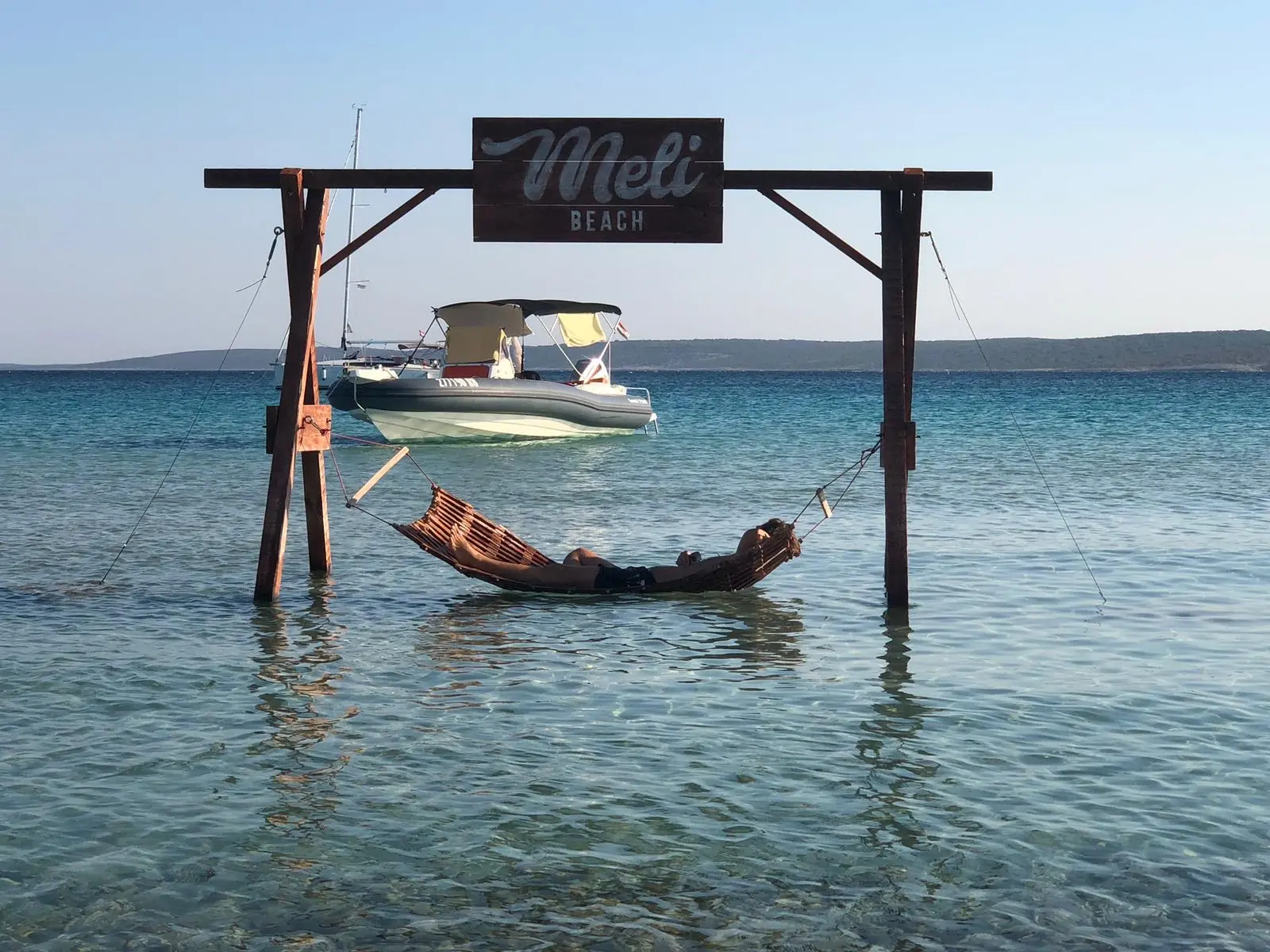 Schaukel am Meer auf Rab mit Boot im Hintergrund