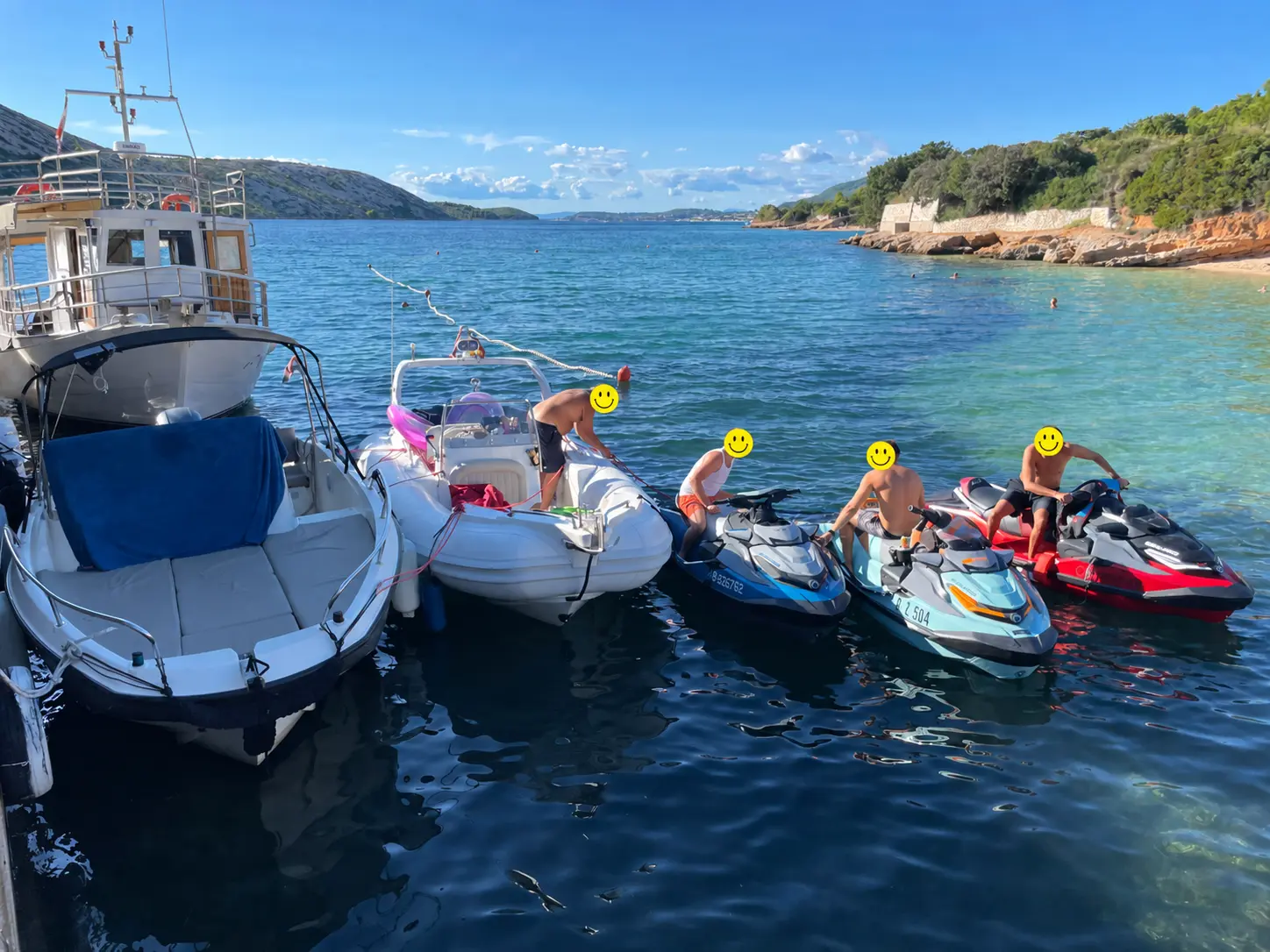 Boote und Jetskis am Ufer, Gesichter mit Smileys verdeckt